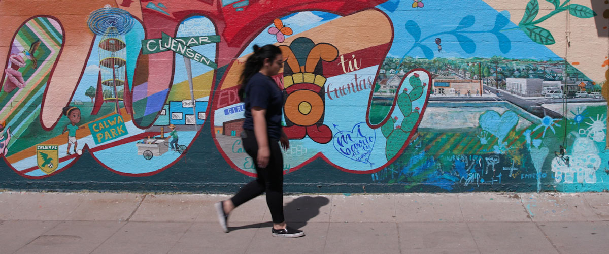 A woman walking past a hand painted wall.